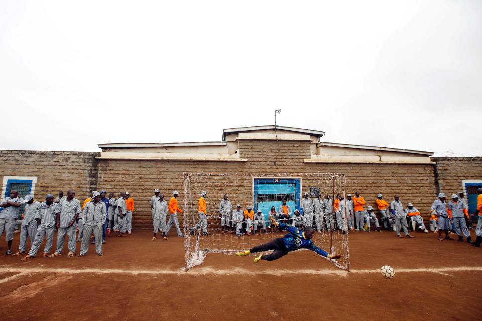<p>A goalkeeper jumps for the ball during warm-up before the start of a mock World Cup soccer match between Russia and Saudi Arabia during a soccer tournament involving eight prison teams at the Kamiti Maximum Security Prison, near Nairobi, Kenya, on June 14, 2018. (Photo: Baz Ratner/Reuters) </p>