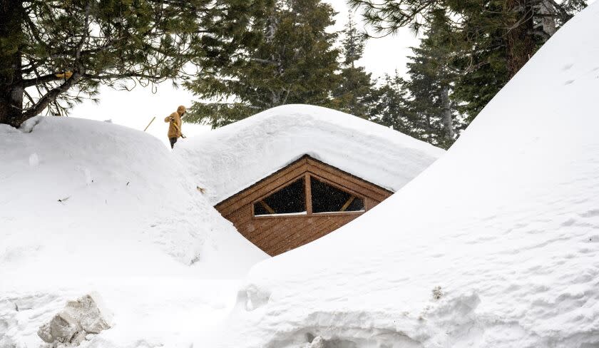 A resident clears snow off the roof of his entombed home in Mammoth Lakes