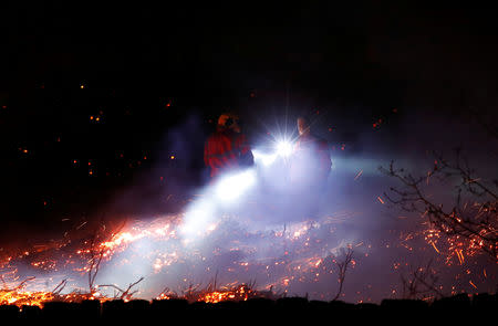 Firefighters tackle a fire on a patch of moorland above the village of Uppermill, Britain, April 22, 2019. REUTERS/Phil Noble
