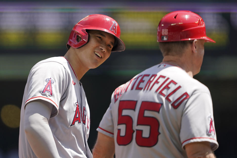 Los Angeles Angels' Shohei Ohtani, left, talks with third base coach Brian Butterfield while on base during the first inning of a baseball game against the Seattle Mariners, Sunday, July 11, 2021, in Seattle. (AP Photo/Ted S. Warren)