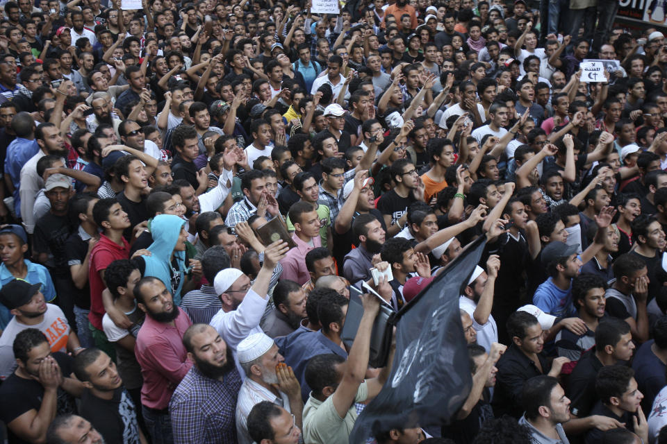 Protesters chant slogans outside the U.S. embassy in Cairo, Egypt, Tuesday, Sept. 11, 2012. Egyptian protesters, largely ultra conservative Islamists, have climbed the walls of the U.S. embassy in Cairo, went into the courtyard and brought down the flag, replacing it with a black flag with Islamic inscription, in protest of a film deemed offensive of Islam. (AP Photo/Mohammed Abu Zaid)