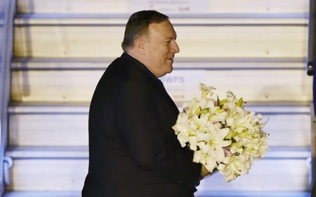 U.S. Secretary of State Mike Pompeo holds a bouquet upon his arrival at an airport in New Delhi