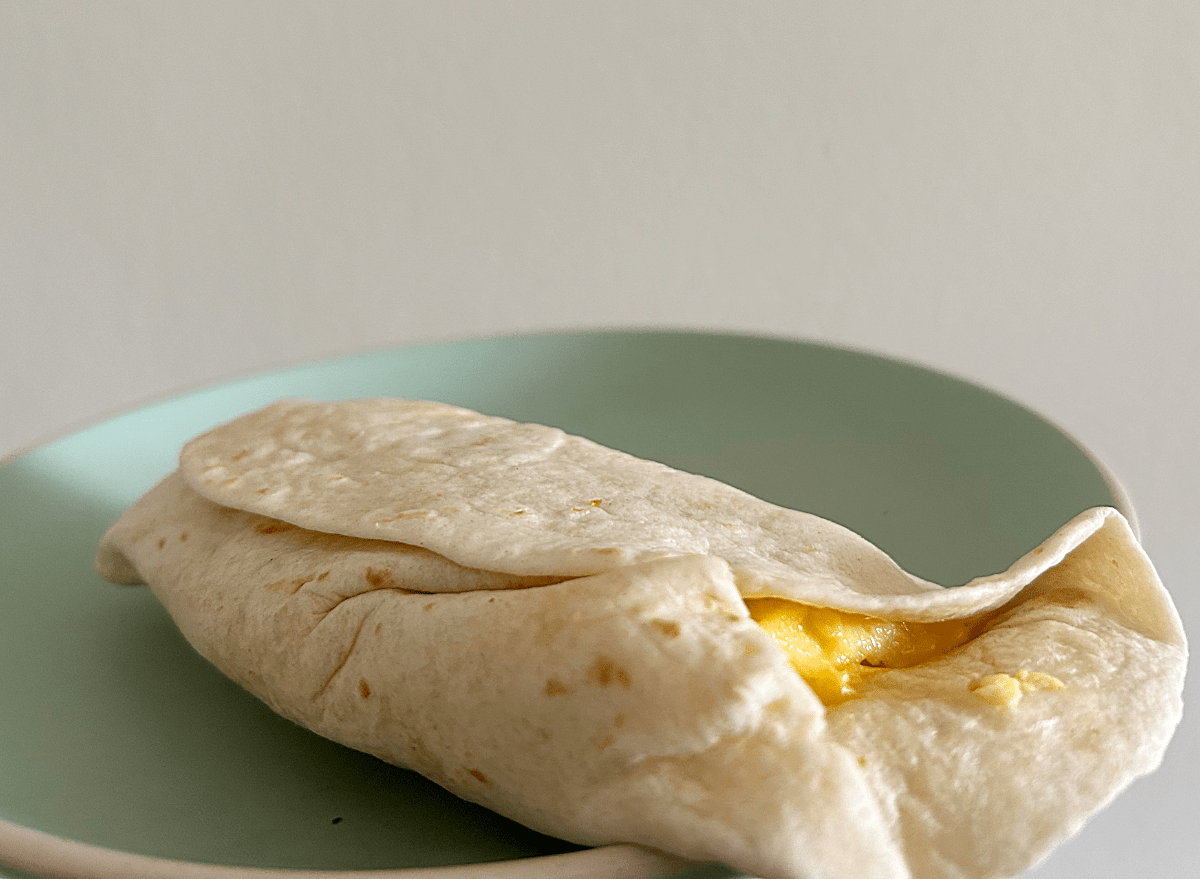 a burger king breakfast burrito on a green plate.