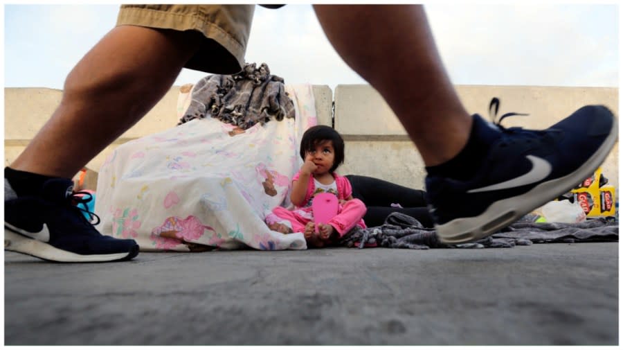 <sup>A pedestrian on the Matamoros International Bridge passes Jennifer, 2, from Guatemala seeking asylum in the United States with her mother June 29, 2018, in Matamoros, Mexico. (Eric Gay, Associated Press file)</sup>