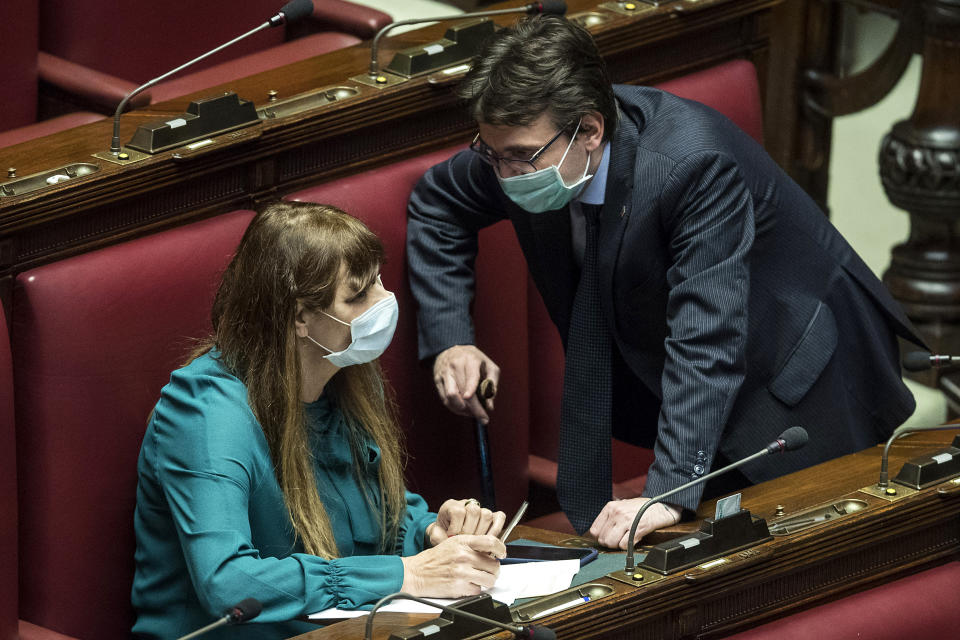 Lawmakers Matteo Dall'Osso, right, and Maria Teresa Baldini wear sanitary mask during a work session in the Italian lower chamber Tuesday, Feb. 25, 2020. Civil protection officials on Tuesday reported a large jump of cases in Italy, from 222 to 283. Seven people have died, all of them elderly people suffering other pathologies. (Roberto Monaldo/LaPresse via AP)