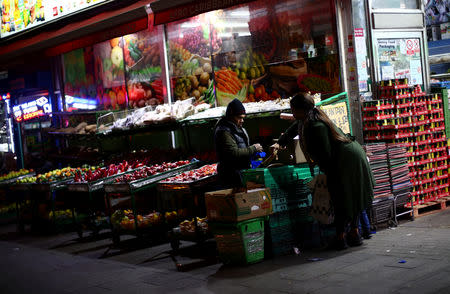 A worker serves a customer at a fruit and vegetable shop on a high street in Dagenham, east London, Britain, March 18, 2019. REUTERS/Hannah McKay