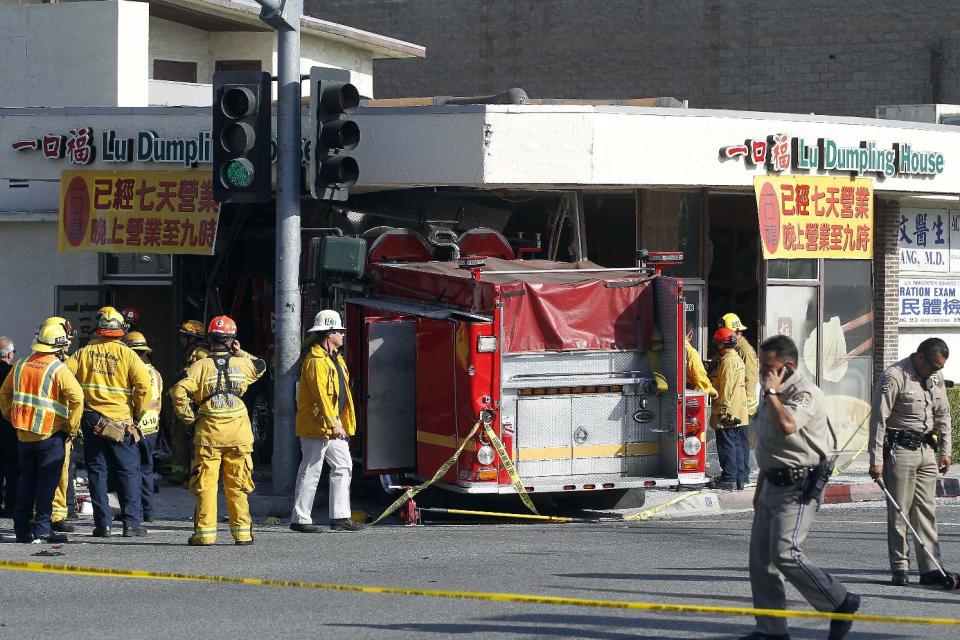 Firefighters and other officials work the scene of an accident where two firetrucks answering a call collided en route to a fire Wednesday, April 16, 2014, in Monterrey Park, Calif. The collision sent one firetruck careening into a restaurant, leaving 14 people, including several firefighters, injured. (AP Photo/Nick Ut)