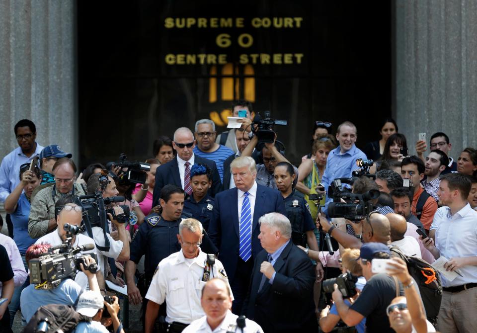 Donald Trump leaving the Supreme Court surrounded by security, photographers, and reporters.