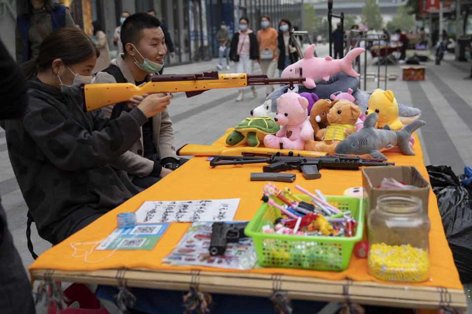 Residents wearing masks to protect from the coronavirus shoot at balloons with a air rifle in Wuhan, China, on Sunday, Oct. 18, 2020. (AP Photo/Ng Han Guan)