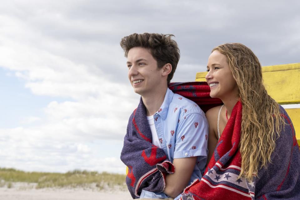 Jennifer Lawrence and Andrew Feldman sit on a beach during a scene from the movie No Hard Feelings.