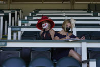 Two women look at a program before the 146th running of the Kentucky Derby at Churchill Downs, Saturday, Sept. 5, 2020, in Louisville, Ky. (AP Photo/Charlie Riedel)