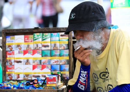 A vendor smokes beside his cigarette stall, while waiting along a main street, in metro Manila, Philippines May 19, 2017. REUTERS/Romeo Ranoco