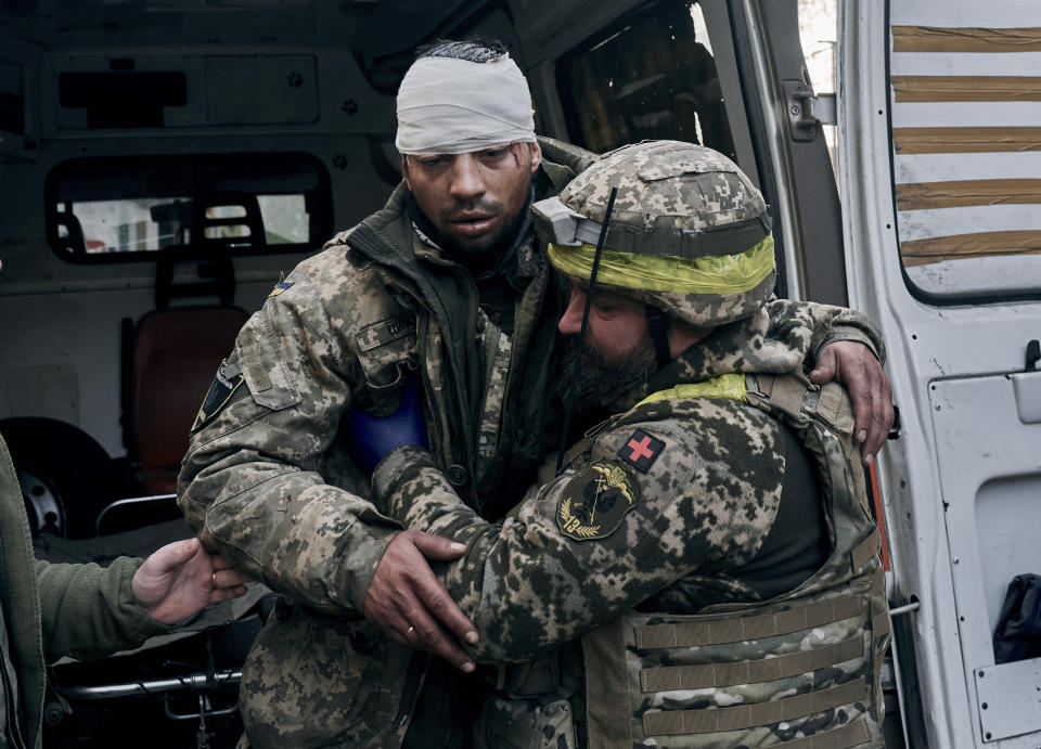 A Ukrainian soldier helps a wounded soldier at a hospital in Bakhmut, Donetsk region, Ukraine, Wednesday, Nov. 9, 2022. (AP Photo/LIBKOS)