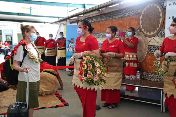 PHOTO: An international visitor is welcomed with a kahoa (garlands) by Tonga Ministry of Tourism staff upon arriving in Tonga from Auckland, New Zealand, on the first flight under the new open border policy at Fua'amotu International Airport, Aug. 1, 2022 (Linny Folau/Matangi Tonga/AFP via Getty Images)