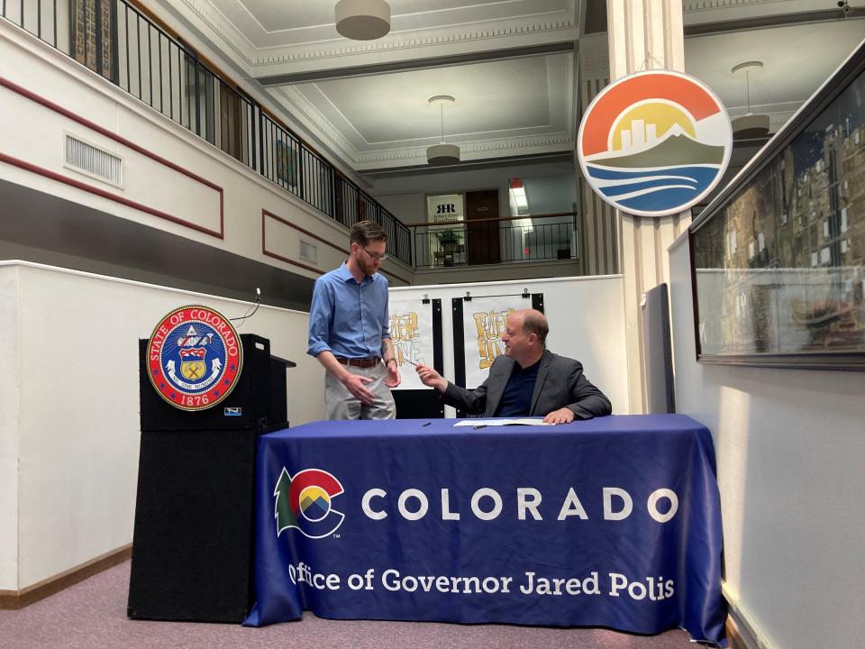 Colorado Gov. Jared Polis hands the pen he signed a bill into law with to state Sen. Nick Hinrichsen at the headquarters of Pueblo Economic Development Corporation on May 23, 2023.