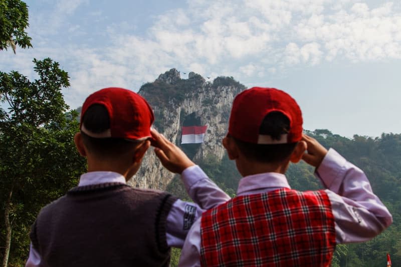 Residents and students salutes as climbing athletes community unfurl a large national flag during a ceremony for Indonesia's 79th Independence Day in Tebing Hawu, Bandung, West Java. Algi Febri Sugita/ZUMA Press Wire/dpa