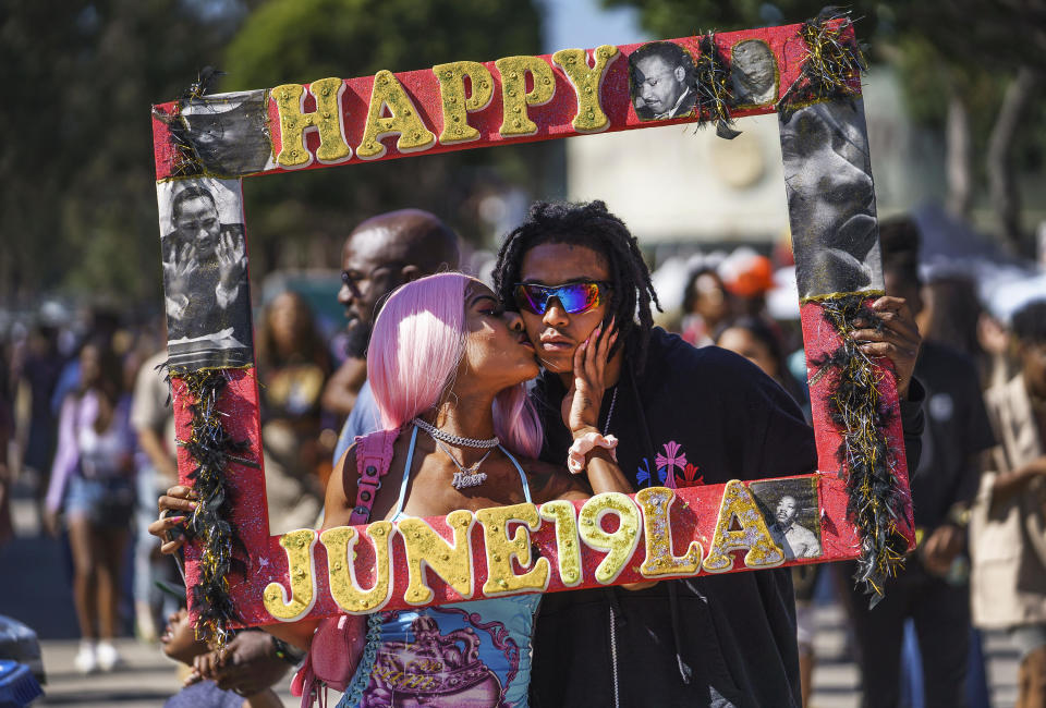 Daisa Chantel kisses Anthony Beltran as they take a picture to celebrate Juneteenth at Leimert Park in Los Angeles on Saturday, June 18, 2022. / Credit: Damian Dovarganes / AP