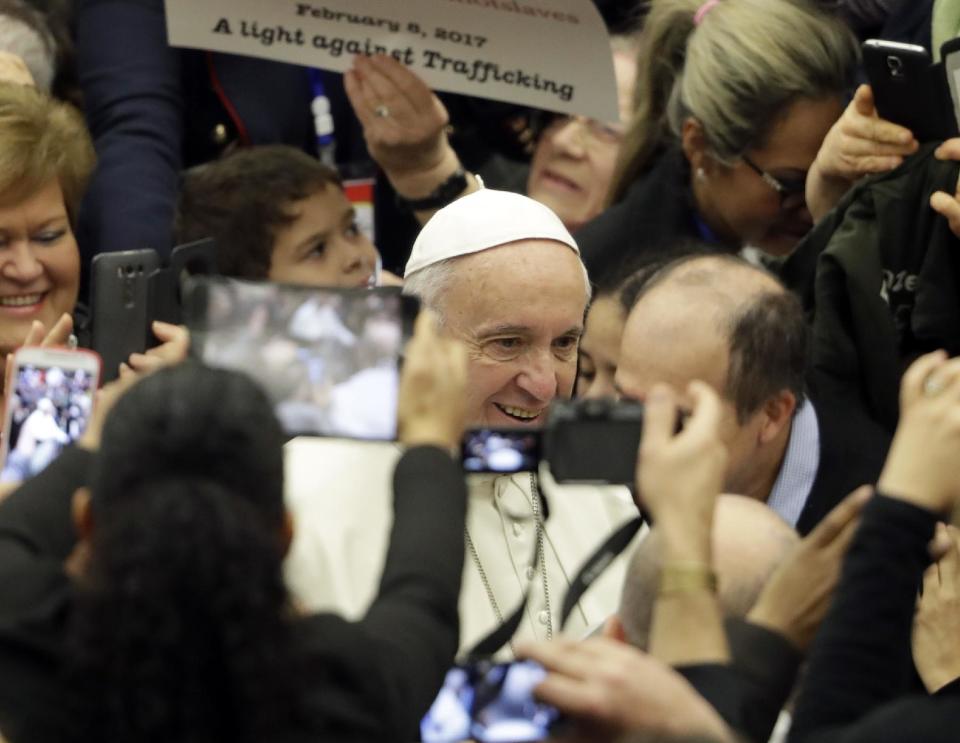 Pope Francis is surrounded by faithful, including one holding a poster against human trafficking, during his weekly general audience in Paul VI Hall, at the Vatican, Wednesday, Feb. 8, 2017. The Vatican has been hosting a conference on human trafficking as part of Francis' efforts to crack down on trafficking in humans and organs. (AP Photo/Andrew Medichini)