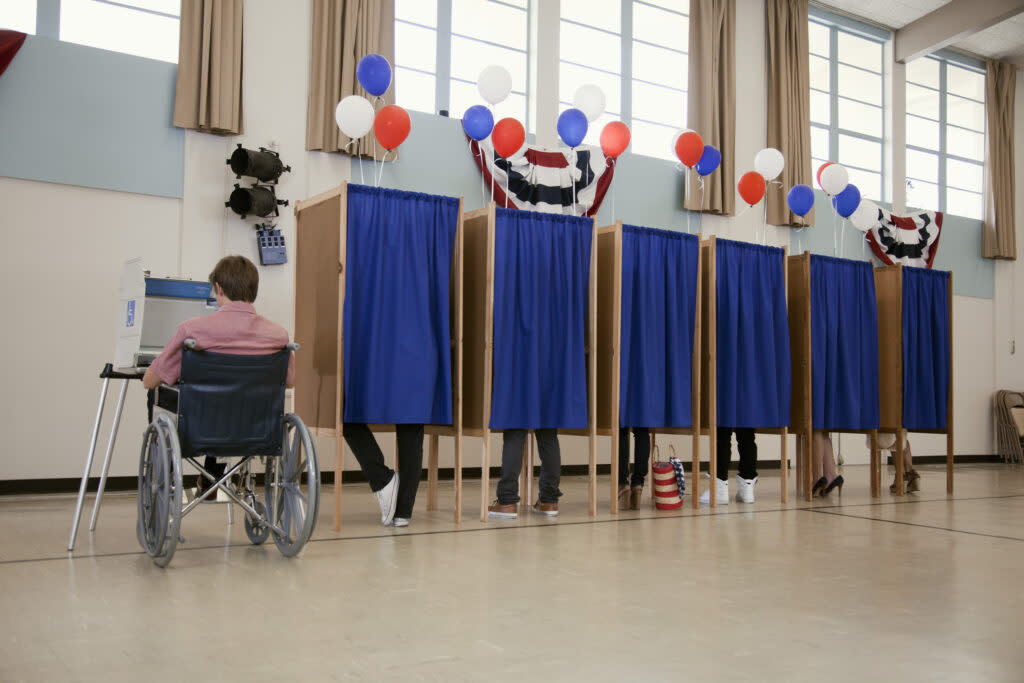 People voting in polling place with a person in a wheelchair on the left