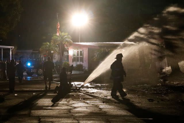 <p>OCTAVIO JONES/AFP via Getty</p> Firefighters work to put out a fire after a small plane crashed into a mobile home park in Clearwater, Florida