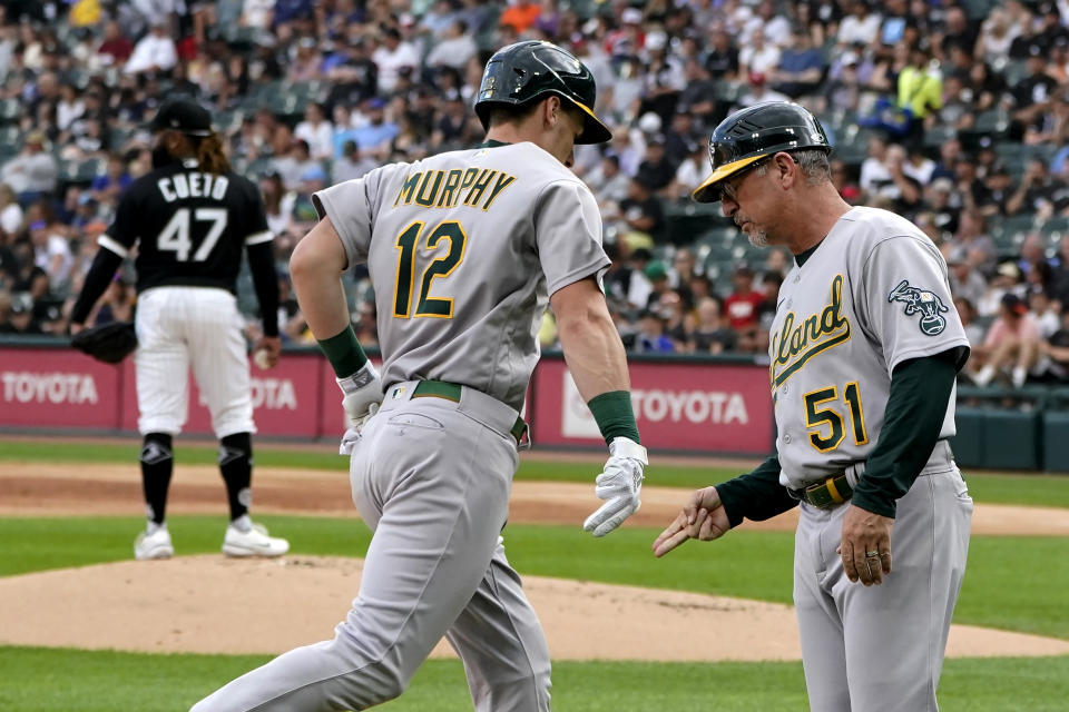 Oakland Athletics' Sean Murphy (12) celebrates his home run with third base coach Darren Bush off Chicago White Sox starting pitcher Johnny Cueto (47) during the first inning of a baseball game Saturday, July 30, 2022, in Chicago. (AP Photo/Charles Rex Arbogast)