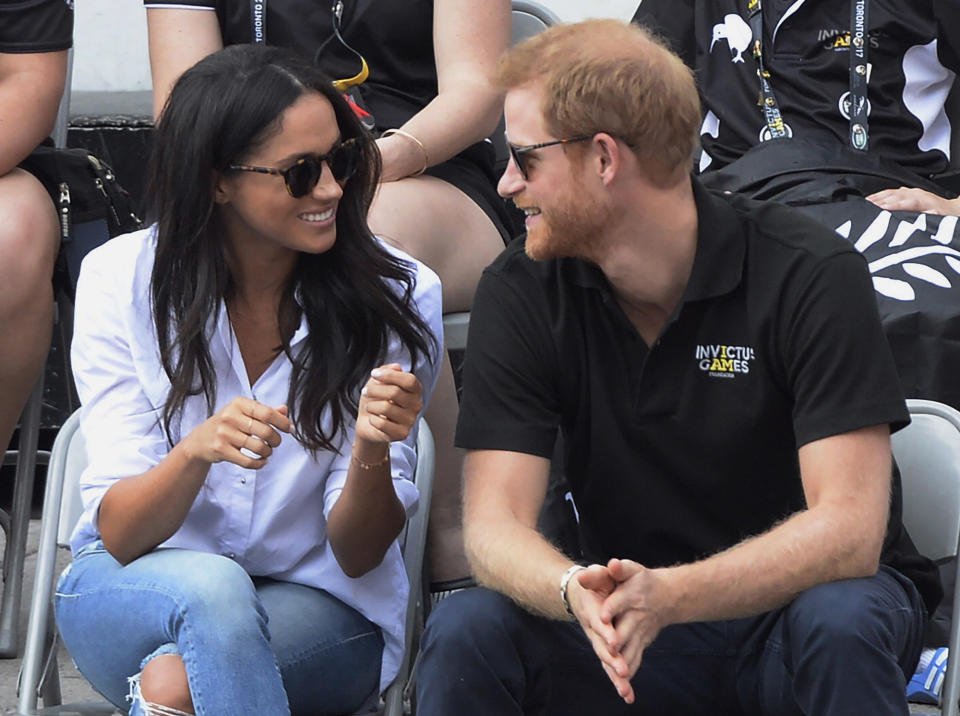 FILE - In this Monday, Sept. 25, 2017 file photo, Britain's Prince Harry and his girlfriend Meghan Markle attend a wheelchair tennis event at the Invictus Games in Toronto. Princess Diana’s little boy _ the devil-may-care red-haired prince with the charming smile _ is about to become a father. The arrival of the first child for Prince Harry and his wife Meghan will complete the transformation of Harry from troubled teen to family man, from source of concern to source of national pride. (Nathan Denette/The Canadian Press via AP, File)