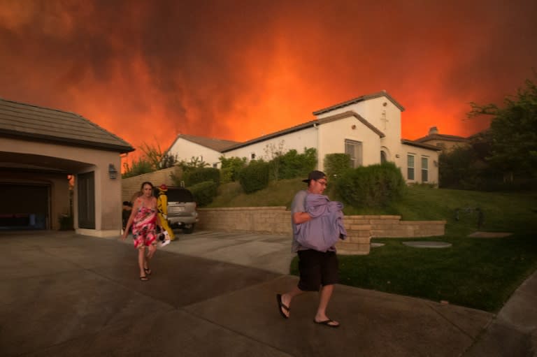 Residents flee their home as flames from the blaze dubbed "Sand Fire" rages, on July 23 2016 near Santa Clarita, California