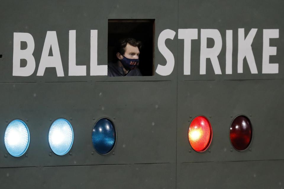 The scorekeeper wears a mask as he watches play from the left field scoreboard at Fenway Park during the eighth inning of a baseball game between the Boston Red Sox and the New York Yankees, Friday, Sept. 18, 2020, in Boston. (AP Photo/Michael Dwyer)