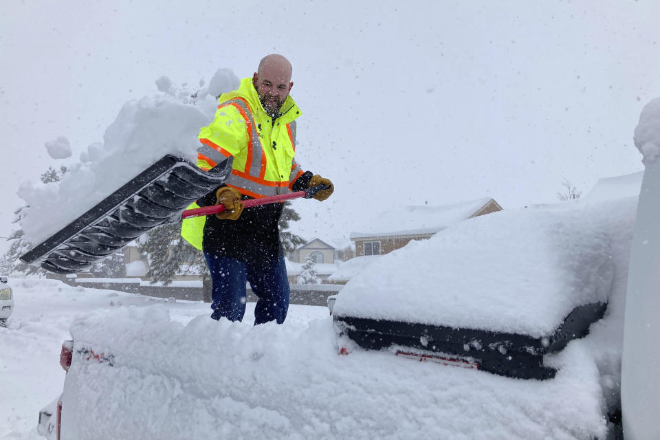 Ryan McMillan, unloads snow from a truck bed in Bellemont, Arizona, on Thursday, Feb. 8, 2024. Storms dumped heavy snow in the region and rain in the deserts of Arizona. (AP Photo/Felicia Fonseca)
