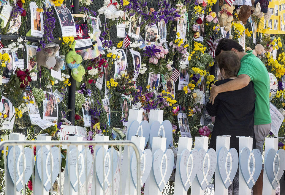 FILE - In this Thursday July 8, 2021, file photo, people mourn at the memorial wall for the victims of the Champlain Towers South collapse, in Surfside, Fla. Families waiting in agony for news on relatives who were in the Florida condo building when it collapsed are turning to each other for support. (Pedro Portal/Miami Herald via AP, File)