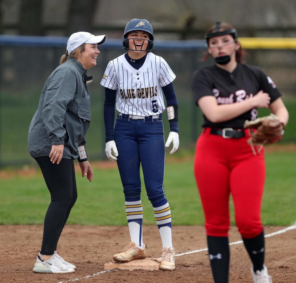 Tallmadge's Leila Staszak celebrates with her coach Briittany Lightel at third base during the first inning of a high school softball game against Kent Roosevelt, Wednesday, April 10, 2024, in Tallmadge, Ohio.