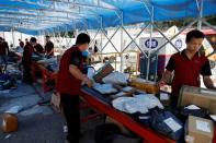 Delivery workers sort packages on a conveyor belt, ahead of the "618" shopping festival, at a logistics station in Beijing