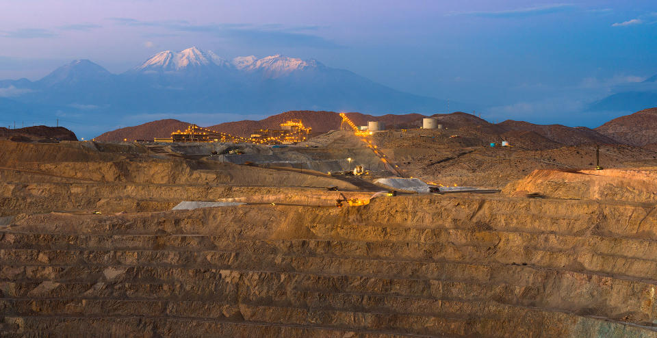 Open-pit mine with mountains in the background.