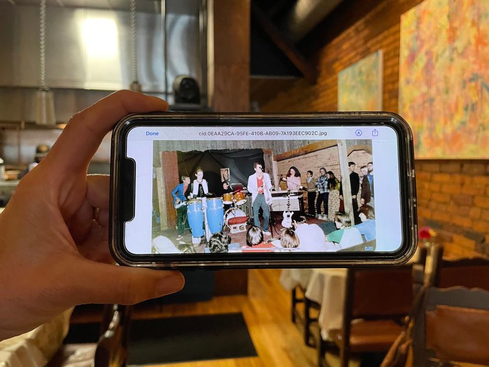 Last Resort Grill co-owner Melissa Clegg uses her phone to display a photograph by Curtis Knapp of a B-52s gig that took place in the building during its years as a music venue.