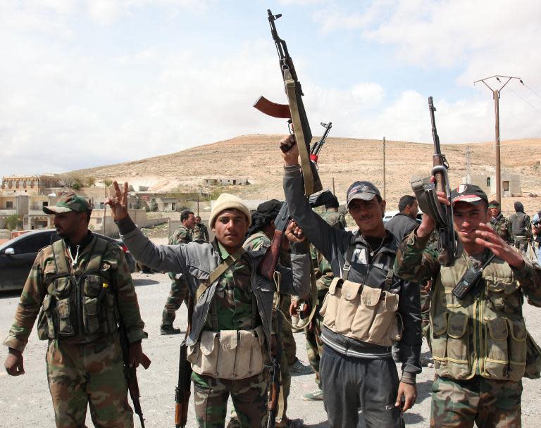 Syrian government forces celebrate in al-Sarkha village, northeast of Damascus, after taking control of the village on April 14, 2014 before moving in to recapture the ancient Christian town of Maalula