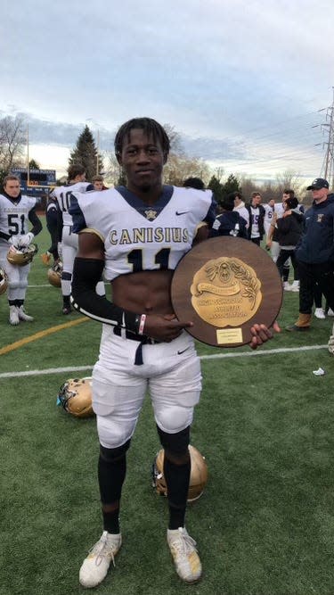 Wisken Whited in 2019 with the plaque for the Catholic state championship.