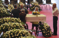 People stand by a small white coffin of a victim of a collapsed highway bridge prior to the start of the funeral service, in Genoa, Italy, Saturday, Aug. 18, 2018. Saturday has been declared a national day of mourning in Italy and includes a state funeral at the industrial port city's fair grounds for those who plunged to their deaths as the 45-meter (150-foot) tall Morandi Bridge gave way Tuesday. (AP Photo/Gregorio Borgia)