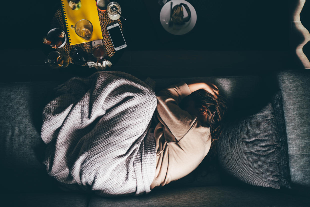 Sad woman lying on sofa at home.