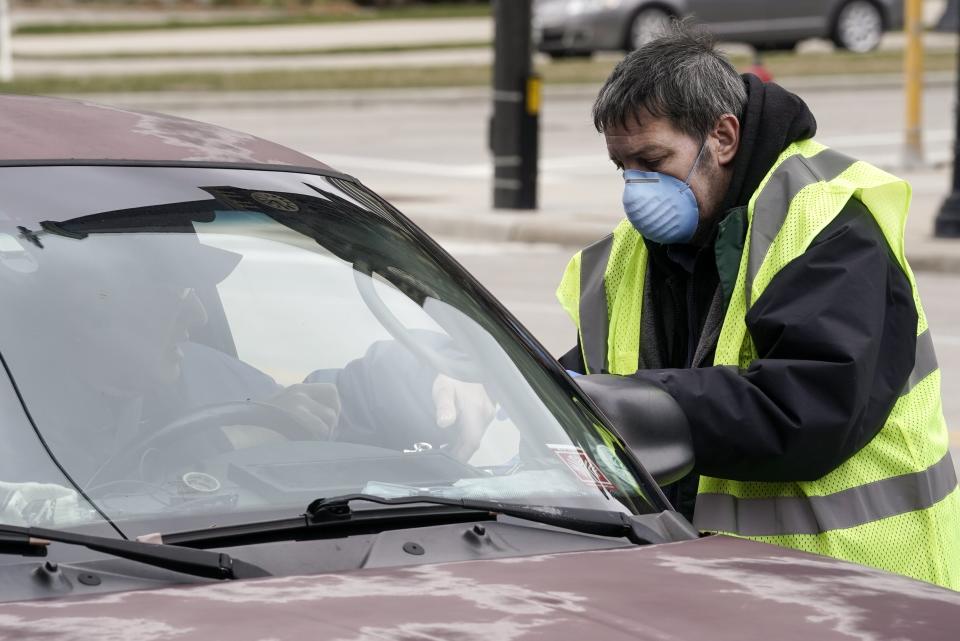 A worker helps a drive-up voter outside the Frank P. Zeidler Municipal Building on March 30 in Milwaukee. The city is now allowing drive-up early voting for the state's April 7 election. (Photo: ASSOCIATED PRESS)