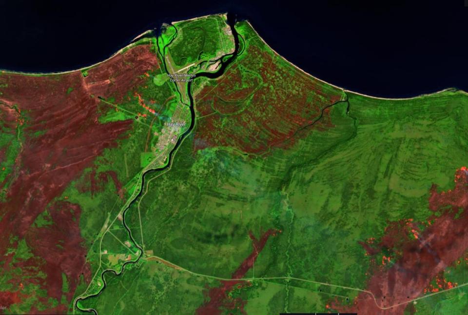 Satellite imagery shows wildfire actively burning a short distance from the town and West Channel. To the east, the wildfire has started to come up toward the shore of Great Slave Lake.