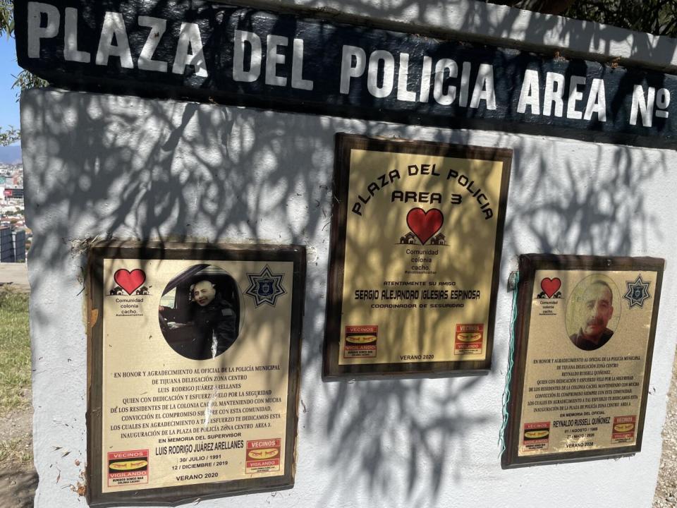 A white wall bears three plaques under the words Plaza del Policia