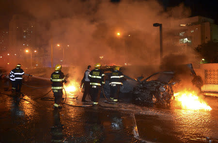 Israeli firefighters work to put out fire on burning cars in an apartment building parking lot after it was hit by what Israeli police say was a rocket fired by Palestinians from the Gaza Strip, in Ashdod July 10, 2014. REUTERS/ Avi Rokach