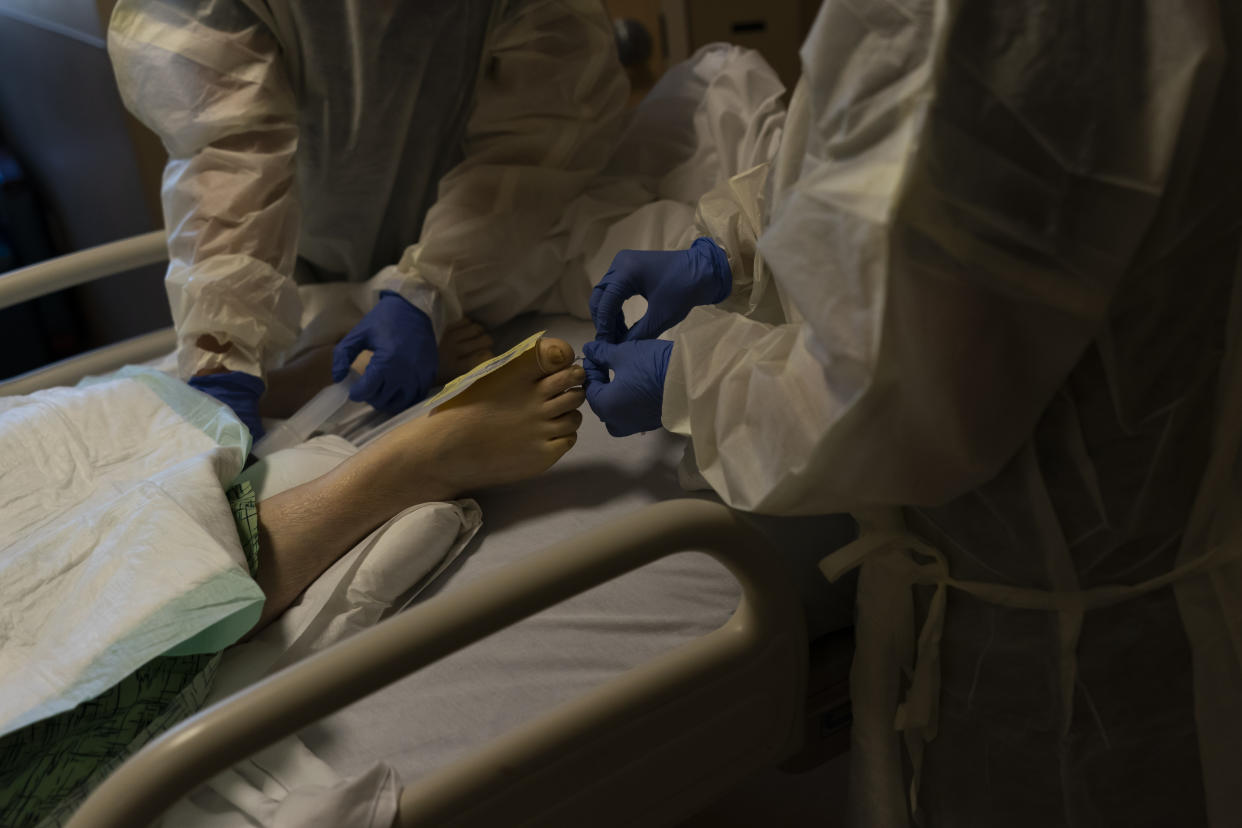 Registered nurses give postmortem care to a deceased COVID-19 patient at Providence Holy Cross Medical Center in Los Angeles, Tuesday, Dec. 14, 2021. (AP Photo/Jae C. Hong)