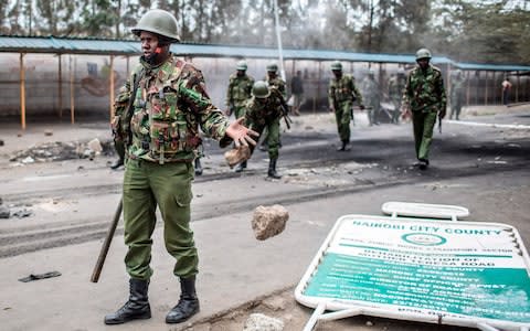 A police officer deflects a stone thrown by a supporter of opposition candidate Raila Odinga - Credit: AFP