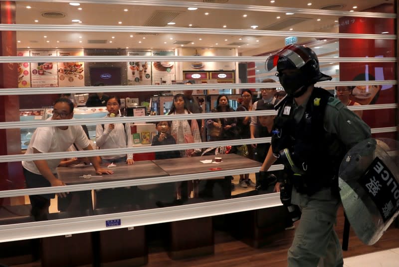 People watch from a restaurant as a riot police officer walks past, at a shopping mall in Tai Po in Hong Kong