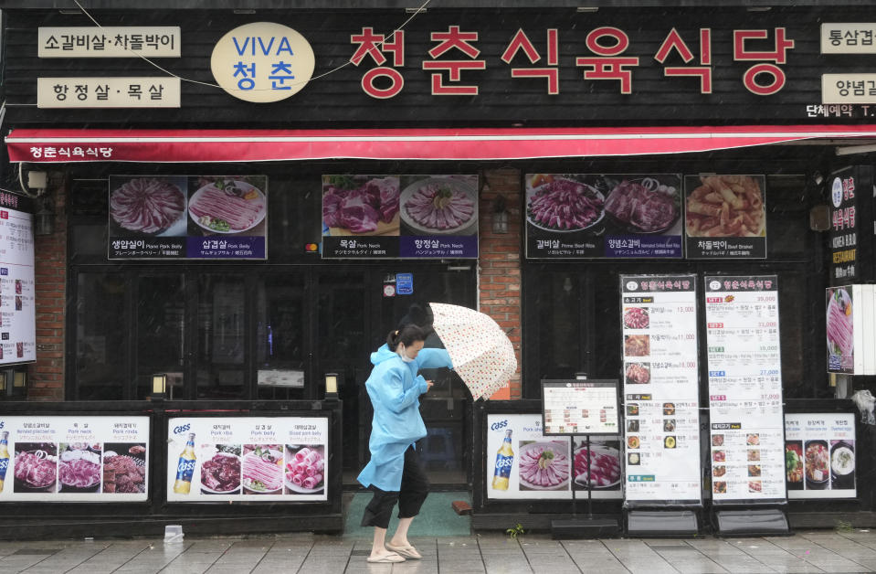 A woman struggles to hold onto her umbrella in the rain and wind as the tropical storm named Khanun approaches to the Korean Peninsular, in Busan, Thursday, Aug. 10, 2023. (AP Photo/Ahn Young-joon)