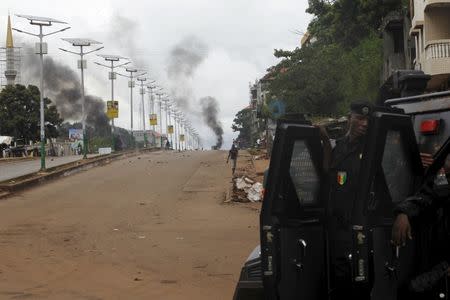 Guinea's security forces are seen as smoke billows on a street in Bambeto during a protest after opposition candidates called on Monday for the results of the election to be scrapped due to fraud, in Conakry October 13, 2015. REUTERS/Luc Gnago