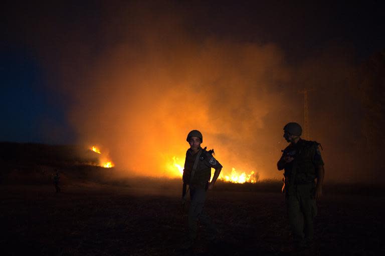 Israeli border guards inspect a field near the southern Israeli city of Sderot on August 20, 2014, after it was hit by rockets fired by Palestinian militants from the Gaza strip