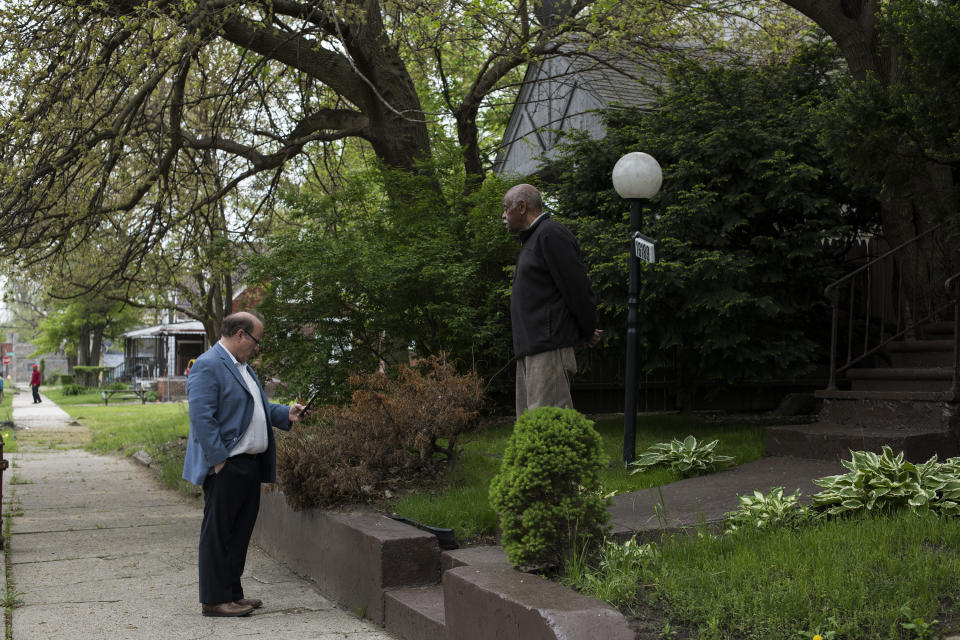 Detroit Mayor Mike Duggan makes a call to his office to address a complaint made by resident Lindsey Herman, 80, right, while giving a tour of Detroit’s Fitzgerald neighborhood. (Photo: Brittany Greeson for Yahoo News)