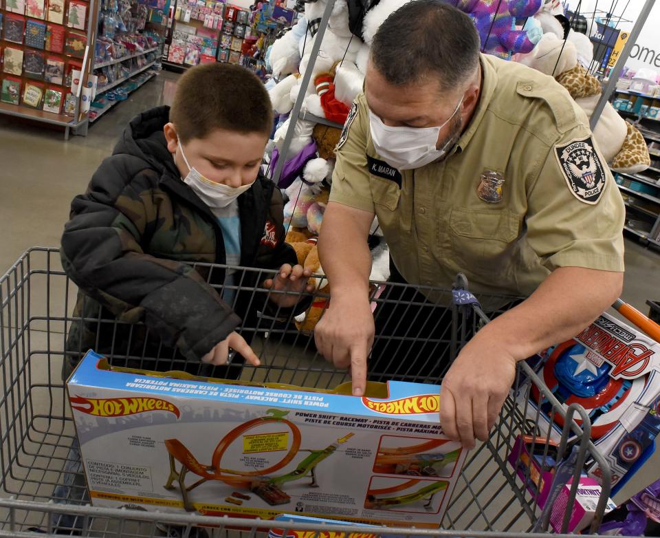 Dundee Elementary Young Five student Nolen Simpson, 5, was excited to talk about race cars with Dundee Police Officer Ken Maran as Nolen participated in Shop With A Cop at Walmart on Thursday. Nolen is with his mother Shalynn Korzowski.